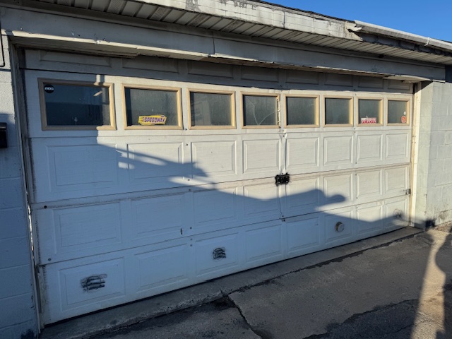 damaged and aged blue garage door with cracked windows
